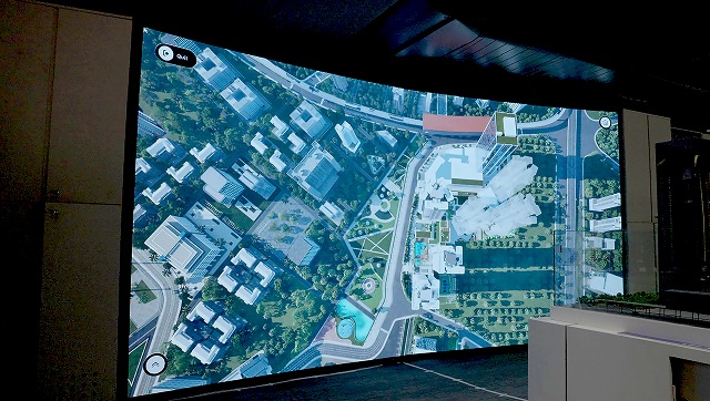 Large LED wall showing an aerial real estate masterplan.
