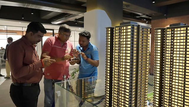 Visitors explore tower models inside a real estate experience center.